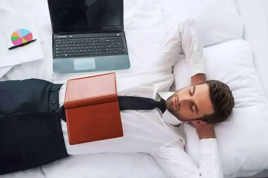 Corporate traveler relaxing on bed with laptop and reports at APX Hotels, ideal for business stays in Sydney with work-life balance and comfort